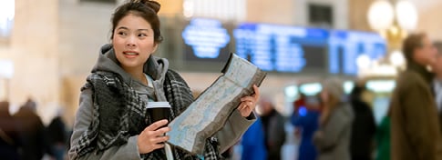 lady standing in a train station holding a cup of coffee