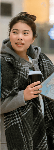 lady standing in a train station holding a cup of coffee